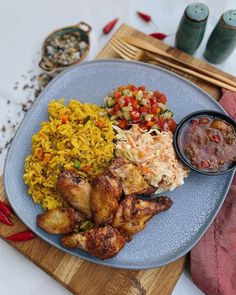 a blue plate topped with chicken and rice next to other food on a wooden cutting board