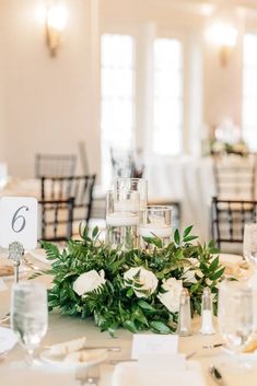 the table is set up for a wedding reception with flowers and candles in centerpieces