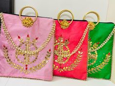 three different colored bags with gold chains and jewels on them, one in pink, the other in green