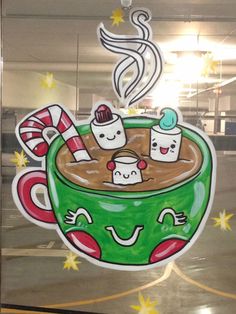 a coffee cup with hot chocolate and marshmallows on it is hanging in the window