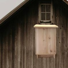 a bird house hanging from the side of a wooden building with a window on it