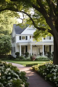 a large white house surrounded by trees and flowers