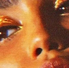 a close up photo of a woman's face with gold glitter on her eyes