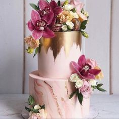 a pink and gold wedding cake with flowers on top