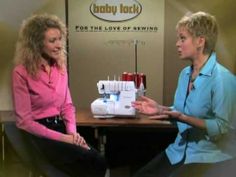 two women sitting at a table with sewing machines in front of them, talking to each other