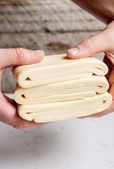 two hands holding small pieces of food in each other's hands on a white surface