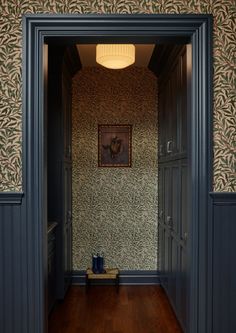 an open door leading into a hallway with wallpaper on the walls and wood floors