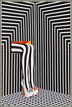 a black and white striped room with high heeled shoes on the floor in front of an abstract wall