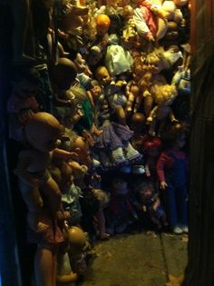 a large amount of dolls are stacked on the wall