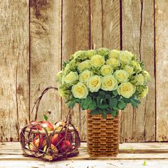 an arrangement of flowers and fruit in a basket