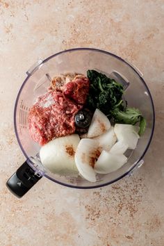 a blender filled with meat and vegetables on top of a marble countertop next to a knife