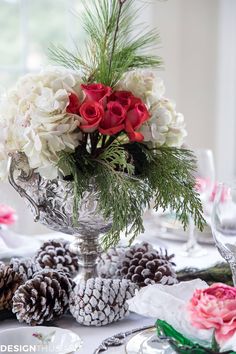 a vase filled with flowers sitting on top of a table next to pine cones and napkins