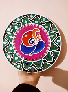 a hand holding up a colorful plate with designs on it