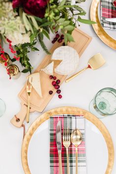 the table is set with plates, silverware and gold utensils on it