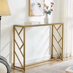 a gold metal and glass console table with flowers on top in a living room setting