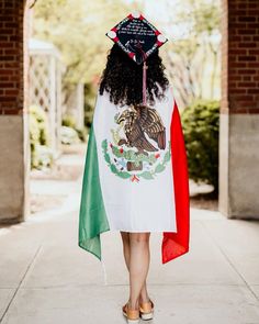 a woman walking down the street wearing a mexican flag graduation gown and holding a tassel