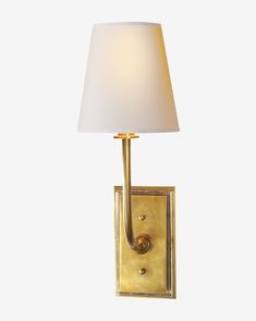 a wall light with a white shade on the side and a gold metal frame around it