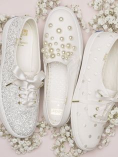 three pairs of white shoes with pearls on them