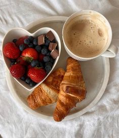 two croissants, strawberries and chocolate are on a plate next to a cup of coffee