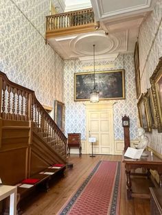 the inside of an old house with stairs and paintings on the wall, carpeted floor