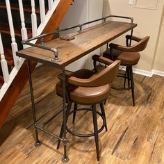 three stools and a table in the middle of a wooden floored area with stairs