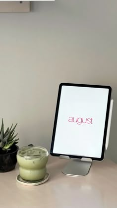 a computer monitor sitting on top of a desk next to a potted plant