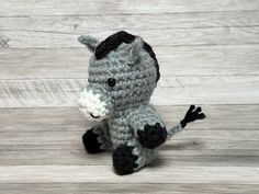 a crocheted gray and black horse sitting on top of a wooden floor