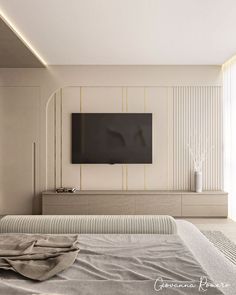 a large flat screen tv mounted to the side of a wall next to a bed