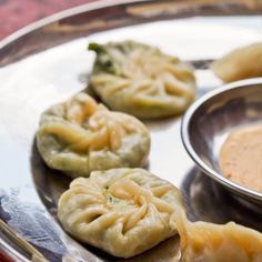 some dumplings are sitting on a plate with dipping sauce