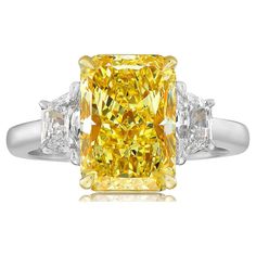 a fancy yellow diamond ring with three baguets on the sides and two diamonds around it