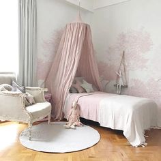 a room with a bed, chair and pink wallpaper on the walls is instagramted