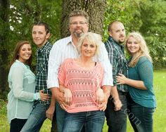 a group of people standing next to each other in front of a tree