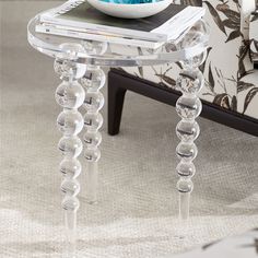 a glass table with a bowl on top of it and magazines in front of it