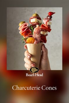 a person holding up a cone filled with meats and cheese on top of it