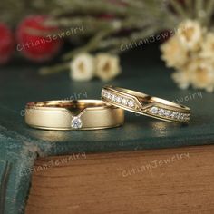 two gold wedding rings sitting on top of a book