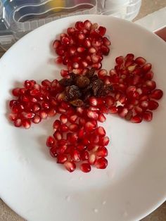 a white plate topped with lots of pomegranate on top of a counter