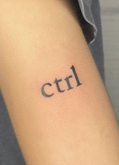 a person with a small tattoo on their arm that says ctrl in cursive font