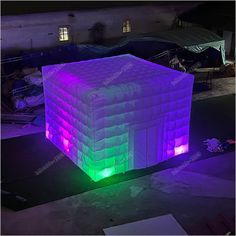 an inflatable cube is lit up with purple and green lights on the floor