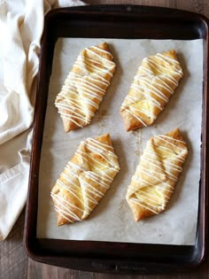 four pieces of pastry sitting on top of a baking pan next to a white towel