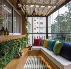 a porch with lots of pillows and plants on it