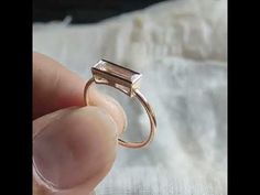 a person is holding a ring with a square shaped stone on the middle of it