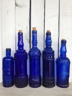 five blue glass bottles lined up on a shelf