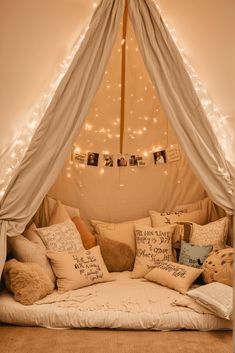 a bed that has some pillows on top of it in a room with lights around the headboard