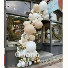 white and gold balloons are hanging from the side of a storefront window in front of a wine bar