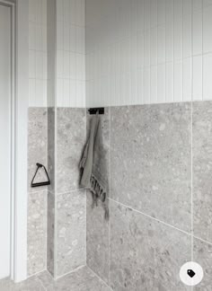 a towel hanging on the side of a shower wall next to a toilet paper dispenser