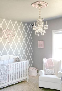 a baby's room with a crib, chair and chandelier