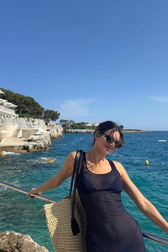 a woman standing on the edge of a cliff next to the ocean