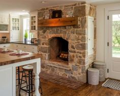 a stone fireplace in the middle of a kitchen