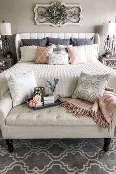 a white bed sitting in a bedroom next to two lamps and pillows on top of it