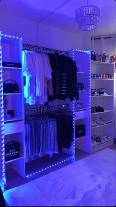 the closet is lit up with blue lights and clothes hanging on shelving unit shelves